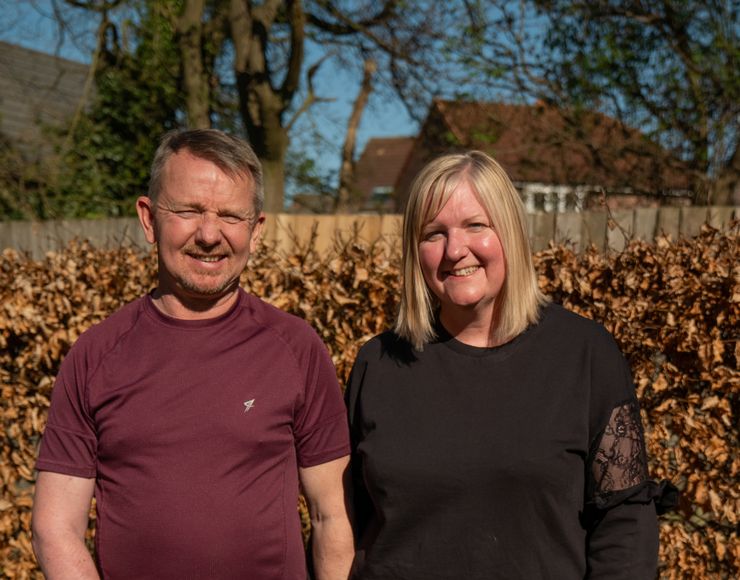 Alan and wife Gina stand together holding hands